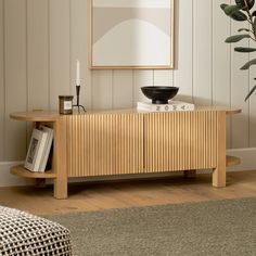 a living room scene with focus on the sideboard and plant in the foreground