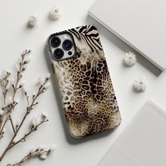 an animal print phone case sitting on top of a white table next to some flowers