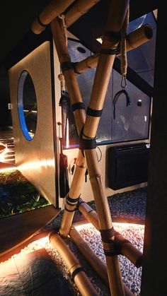 a bamboo structure made out of pipes and wood sticks with lights on the side of it