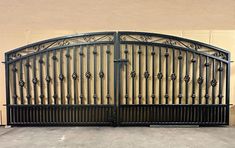 an iron gate is shown in front of a tan wall and cement floored area