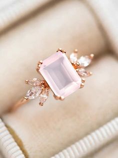 an engagement ring with a pink stone surrounded by white and clear stones in a box