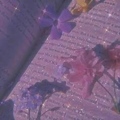 an open book with flowers on the pages and sparkles in the back ground behind it