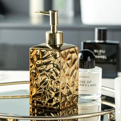 a golden soap dispenser sitting on top of a glass table next to bottles