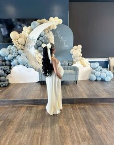 a woman is standing in front of a backdrop with balloons and an arch that reads, i love you to the moon