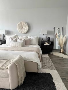 a bedroom with white bedding and pillows on the floor next to a chair, dresser and window