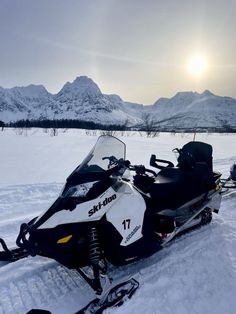 a snowmobile is parked in the snow near mountains