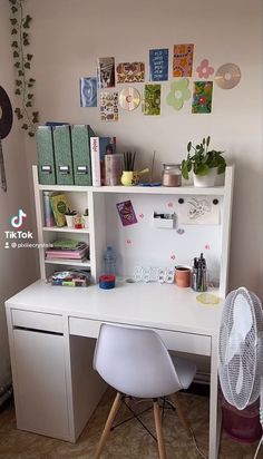 a white desk with a fan and some books on the top shelf next to it