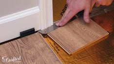 a person is using a knife to cut wood planks on the floor next to a door