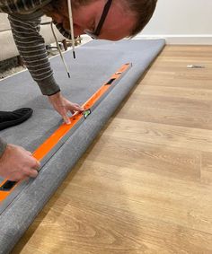 a man is working on an orange and black piece of furniture that he's laying on