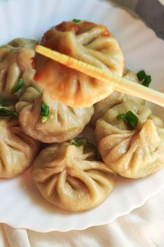 some dumplings are sitting on a plate with chopsticks sticking out of them