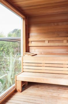 a wooden sauna with two benches next to it and a large window in the background