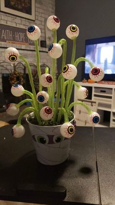 a potted plant with fake eyes and balls in it on a table next to a tv