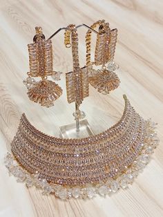 an elaborate necklace and earring set on a wooden table with white wood flooring