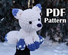 a crocheted white and blue teddy bear sitting in the snow