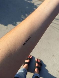 a person with a tattoo on their arm that says be brave in black ink,