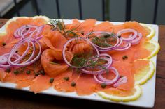 a white plate topped with sliced up salmon and onions