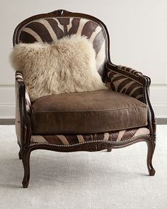 a zebra print chair with a furry pillow on it's back and arm rest