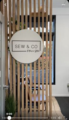 a sign that says sew & co on the side of a wooden fence in front of a window