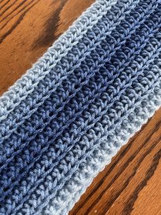 a crocheted blue and white blanket on top of a wooden table