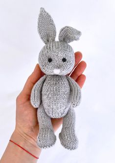 a hand holding a gray knitted bunny