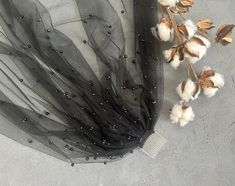 a black tulle with some cotton flowers and a comb on the ground next to it