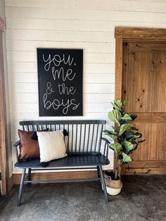 a black and white bench sitting in front of a wooden door next to a potted plant