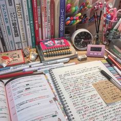 an open book sitting on top of a desk next to many books and pencils