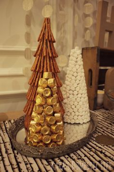 two small christmas trees made out of wine corks on a tray with gold and white decorations