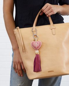 Our Natasha Charm adds a pop of color to your bag or keys with a hand-beaded heart ornament. Mix them up and pile them on to make your own statement! Details & Sizing Hand-beaded heart charm Leather tassel Attached keyring and chain 9" length. Made in Mexico New Consuela Logo We are rolling out a new logo in Spring 2021, and this product is now shipping with an updated version of the CONSUELA logo. Bag Charm With Keys As Gift, Beads Logo, Beaded Heart, New Charmed, Heart Ornament, Luggage Accessories, Leather Tassel, Beautiful Love, Luggage Tags