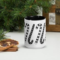 a white and black coffee mug sitting on top of a table next to cinnamons