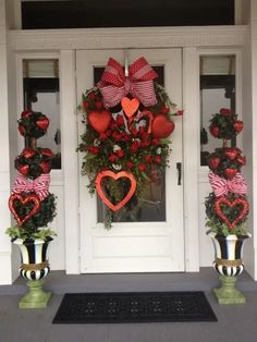 two heart - shaped wreaths on the front door of a house decorated for valentine's day