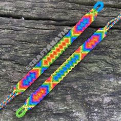 two colorful bracelets sitting on top of a piece of wood