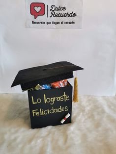 a graduation cap on top of a box filled with candy and candies in front of a sign