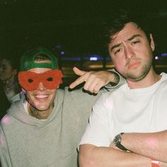 a man and woman with red masks on their faces posing for the camera at night