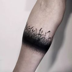 a person with a tattoo on their arm that has grass growing out of the ground