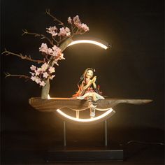 a woman sitting on top of a wooden table next to a tree with pink flowers