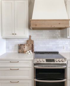 a stove top oven sitting inside of a kitchen next to white cupboards and drawers