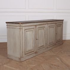 an old white cabinet sitting on top of a hard wood floor next to a wall