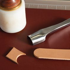 a pair of scissors next to a piece of wood on a table with a jar