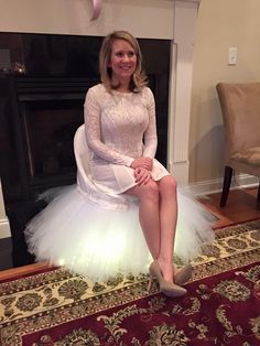 a woman is sitting on a chair wearing a white tulle skirt and high heels