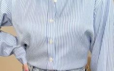 a woman wearing a blue and white striped shirt with her hands in her pockets,