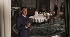 a man in a suit standing next to a table with people sitting at the tables