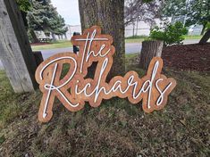 a wooden sign that says the richards on it in front of a tree and grass area