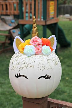 a white pumpkin decorated with flowers and a unicorn's head