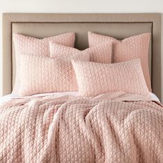 a bed with pink comforters and pillows on it