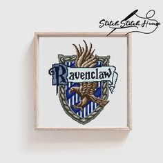 the ravenclaw crest cross stitch pattern is displayed in a wooden frame on a wall