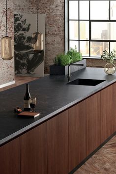 an empty kitchen with black counter tops and wooden cabinets in front of a large window