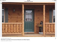 a bear statue sitting on the porch of a log cabin next to a green door