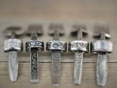 several different types of rings are lined up on a table with other items in the background