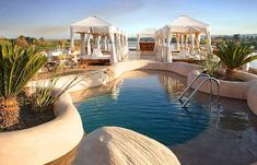 an outdoor swimming pool with gazebos in the background